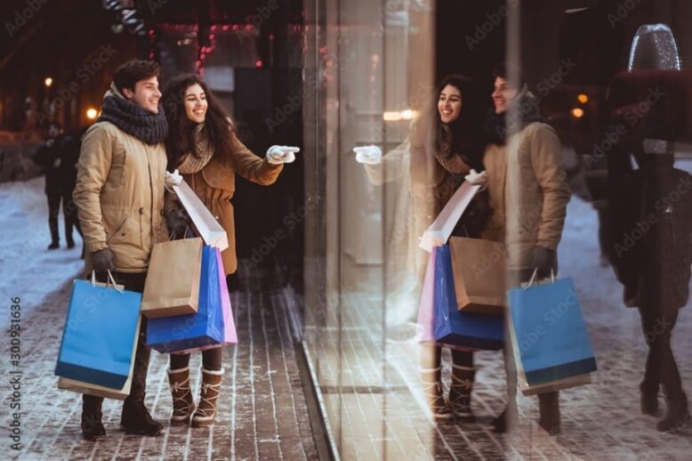 Couple window shopping holding shopping bags in winter Couple window shopping holding shopping bags in winter