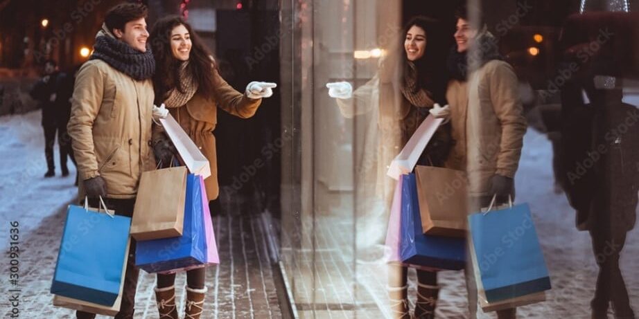 Couple window shopping holding shopping bags in winter