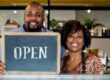 Store Owners holding Open Sign